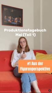 Ein weißer Schriftzug „Produktionstagebuch Mai (Teil 1)“, eine Person auf roter Couch mit Mikro und davor auf orangenem Grund der Schriftzug „#1 Aus der Figurenperspektive“