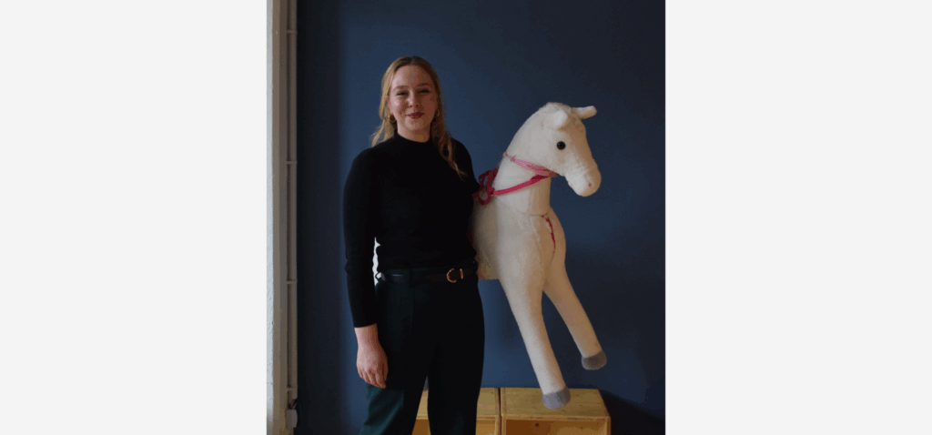 Puppenspielerin Linda Fülle mit einem großen Stoffpferd unter dem linken Arm, sie ist schwarz gekleidet