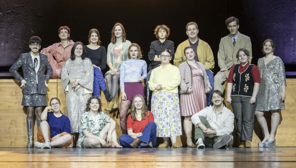 Ensemble (hintere Reihe sitzend v. I. n. r.) Ilai Lorenz (Die Schwägerin), Lina Marie Marschallek (Die Frau), Fee Brünnen (Die Nichte), Vera Jenikejew (Der Polizist | Der Teppichhändler), Simon Heuwing (Der Mann | Yang Sun, ein stellungsloser Flieger), Jannis Clemens (Der Babier Shu Fu | Der Schreiner Lin To) (mittlere Reihe stehend v. I. n. r.) Tekin Karacali (1. Gott | Der Großvater), Theresa Schild (2. Gott | Der Arbeitslose), Lulu Feuser (Shen Te | Shui Ta), Joana José Grunow (Die Witwe Shin), Michelle da Silva (Die Hausbesitzerin Mi Tzü | Frau Yang), Veronika Boichuk (Die Teppichhändlerin | Der Junge | Der Priester), Jamie Cremerius (3. Gott | Der Neffe) (vordere Reihe sitzend v. I. n. r.) Hannah Schüren-Hinkelmann (Der Cousin zweiten Grades), Lea Strobe (Wang, ein Wasserverkäufer), Mila Vischedyk (Die Schwippschwägerin | Die andere Prostituierte), Ben Bruckmann (Der Bruder)