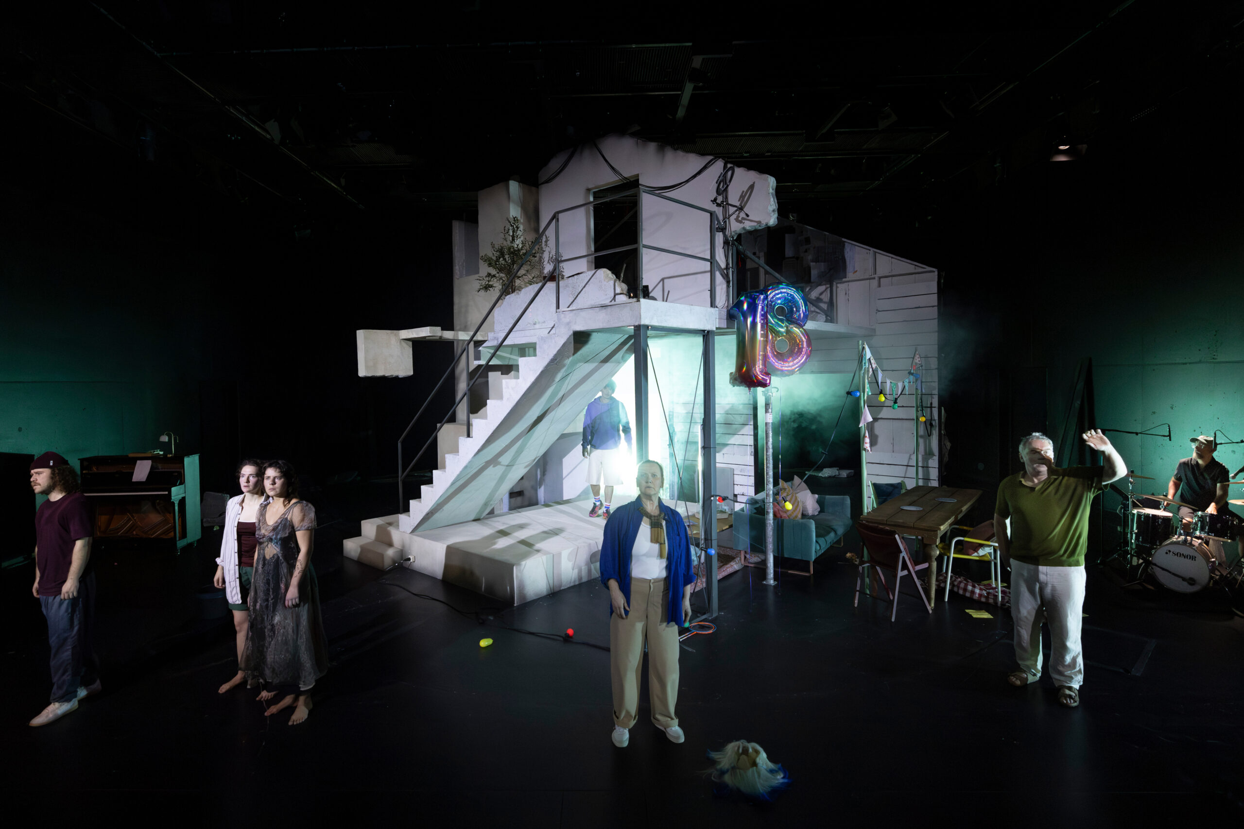 Vier Personen in einer Hauskulisse auf einer Bühne