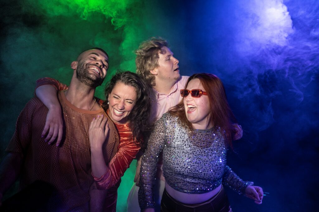 vier Personen feiernd auf einem Bild in grünblauem Nebel