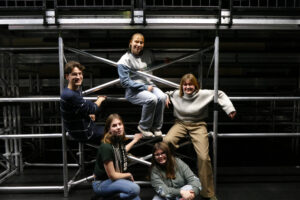 Eine Gruppe fünf junger Menschen, die in einem Bühnengerüst posieren