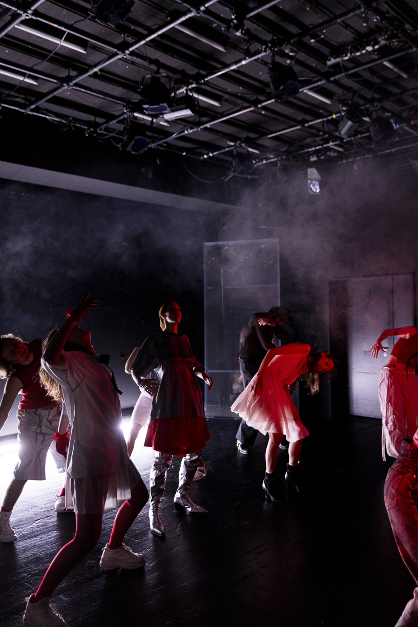 mehrere Darstellende auf einer dunkel, vernebelten Bühne in abstrakten Bewegungen